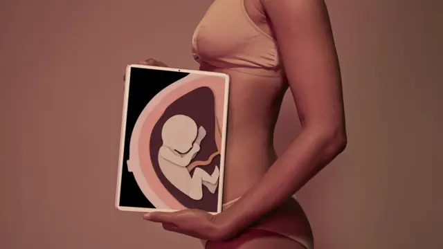 Una mujer sostiene un cartel con la imagen de un bebé.