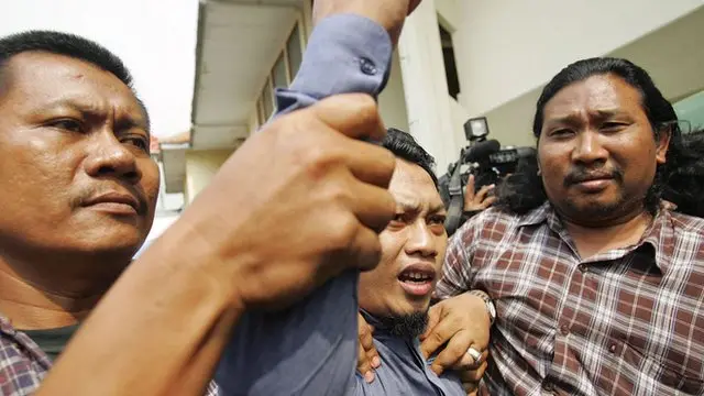 Hassan raising his fist in defiance as he leaves court