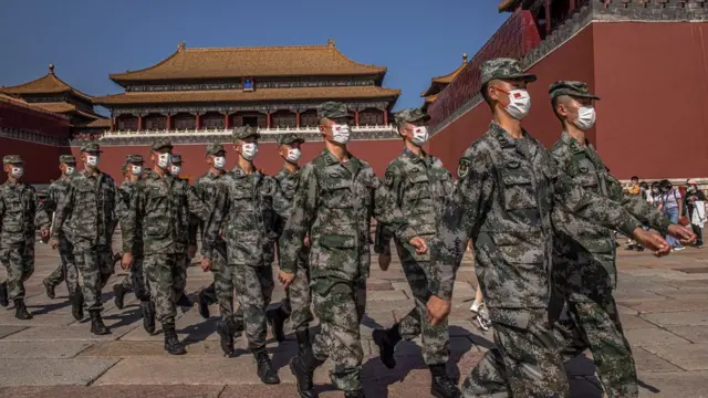 Chinese paramilitary police officers wearing protective face masks march past the entrance to the Forbidden City on National Day, in Beijing, China, 01 October 2021.