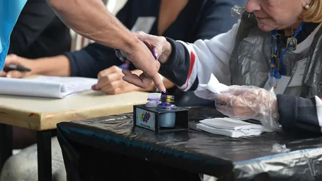 Un votante moja su dedo con tinta indeleble.