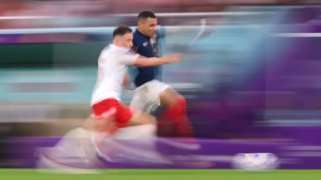 Kylian Mbappé e Matty Cash correndo ao longo da linha lateral - a imagem borrada sugerindo o quão rápido eles estão correndo