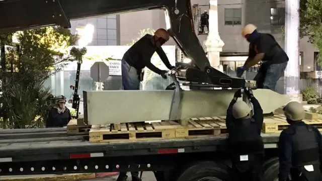 Trabajadores de Nueva Orleans con el rostro cubierto preparando la remoción del monumento de Liberty Place.