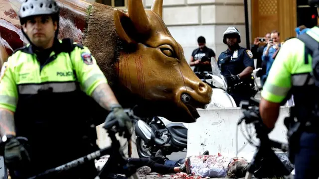 Aktivis perubahan iklim dikelilingi oleh polisi saat berunjuk rasa di depan patung Wlall Street Bull, Manhattan, 07 Oktober 2019.