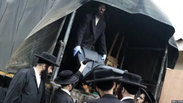 Men from a Jewish community load furniture onto a lorry in San Juan La Laguna