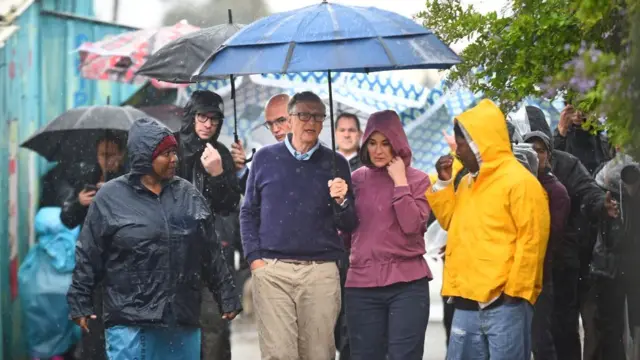 Bill and Melinda Gates brace the rain as they visit the township of Khayelitsha on October 25, 2019 in Cape Town, South Africa