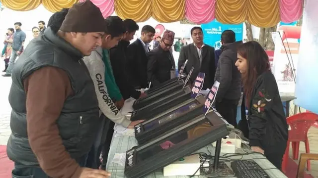 एउटा मेलामा विद्युतीय मतदान मेसिन हेर्दै सर्वसाधारण