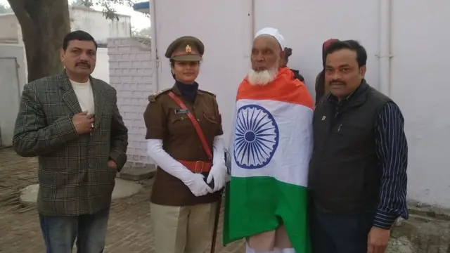 Shareef wrapped in Indian flag being surrounded by police and administrative officials