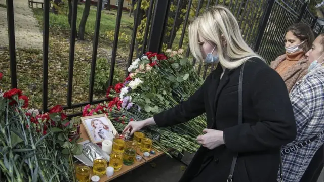 Люди несут цветы и свечи в память о погибших