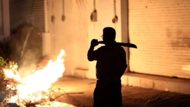 Neighbours stand guard to prevent looting