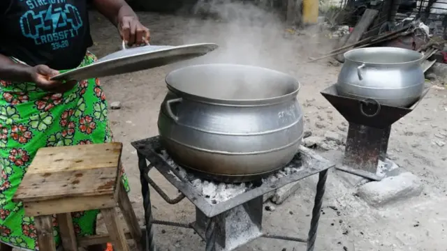 Dans un restaurant, une femme fait bouillir des ignames avant de les piler.