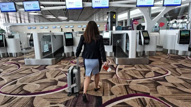 One airport worker wey dey waka go di automated bag-drop counters during media preview for di departure hall of Changi Airport Terminal 4 wey dey newly-build for Singapore.
