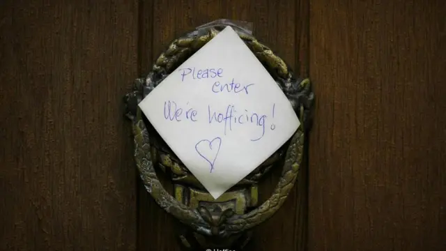 Un papel en la puerta de una casa que dice "Pase adelante. Estamos haciendo hoffice"