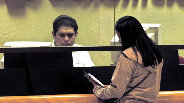 Mujer en un cajero donde atiende un hombre