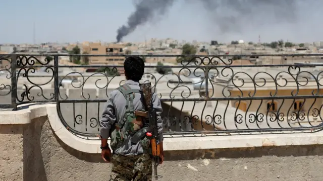 A Kurdish fighter looks out over Raqqa just after an airstrike on the city.