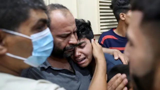 A relative of a Palestinian killed in the Israel-Gaza hostilities is comforted at a hospital in the northern Gaza Strip (10 May 2021)
