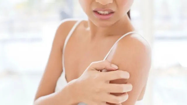 Жінка чухає плече 