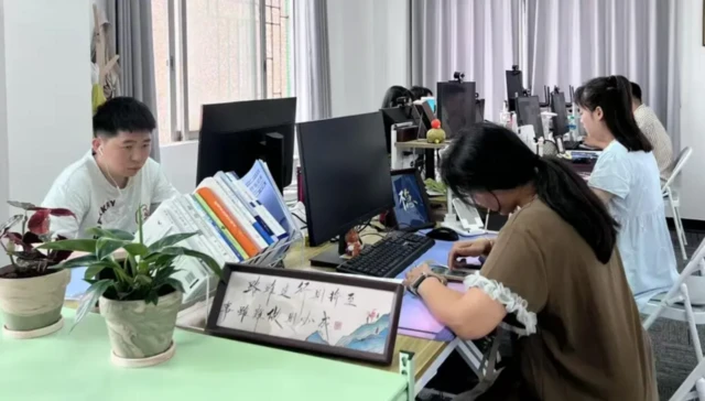 Bilgisayar başında oturan üç Çinli var. 