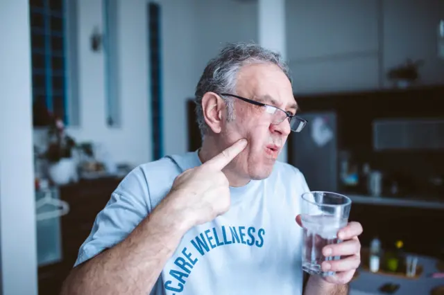 Un hombre señalando que tiene dolor de muela