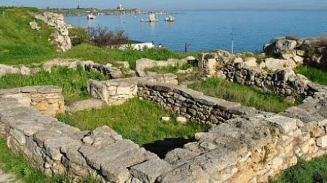 Каменные руины на берегу моря среди зеленой травы