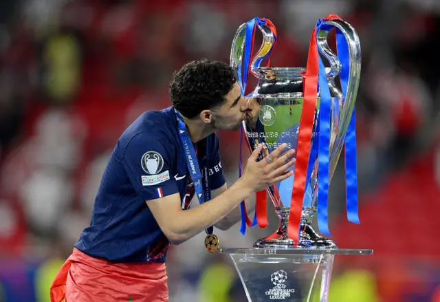 أشرف حكيمي لاعب باريس سان جيرمان يقبل كأس دوري أبطال أوروبا