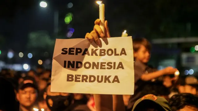 Suporter Delta Sidoarjo memegang lilin saat mengikuti doa bersama di Gelora Delta Sidoarjo, Jawa Timur, Selasa (4/10/2022).
