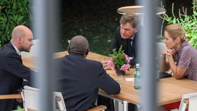 Dört temsilci bir masa etrafında konuşuyor. 