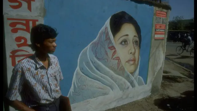 খালেদা জিয়ার দেয়াল চিত্রের পাশে দাঁড়িয়ে একজন যুবক