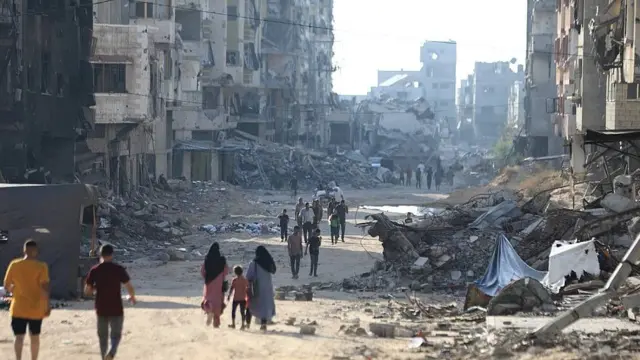 Personas caminando entre edificios en ruinas en la Ciudad de Gaza 