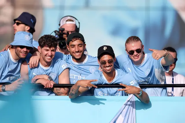 Nico Gonzalez, John Stones, Omar Marmoush, Tijjani Reijnders et Erling Haaland, joueurs de Manchester City, saluent les supporters depuis le bus lors du défilé et de la fête organisée pour célébrer les performances des équipes masculines, féminines et de jeunes de Manchester City durant la saison 2025/26, le 25 mai 2026 à Manchester, en Angleterre.
