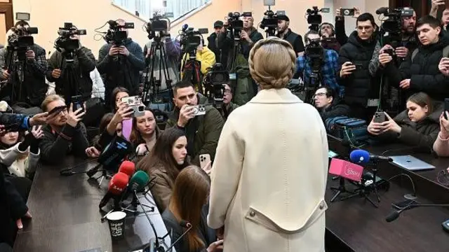 Юлія Тимошенко в суді, одягнена у біле пальто, звертається до журналістів