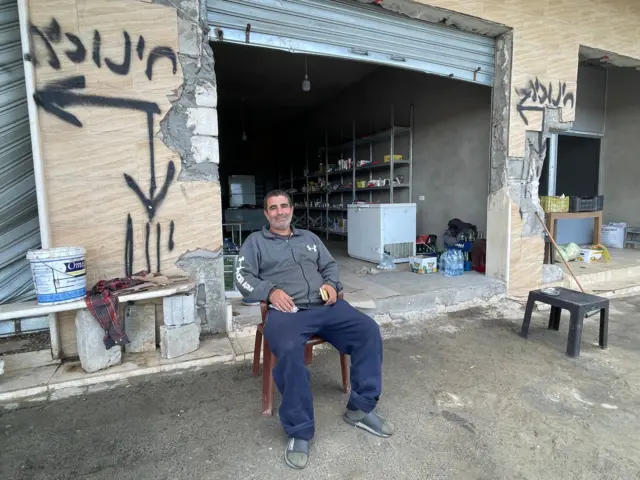 مردی که جلوی مغازه اش نشسته است