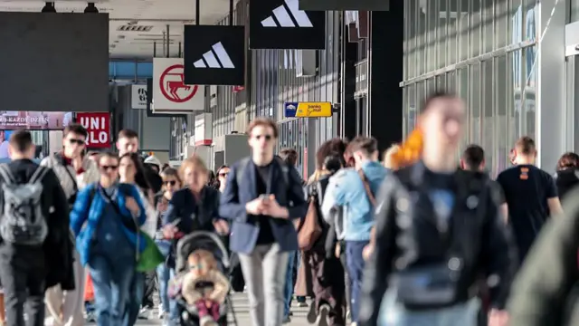 Tłumy ludzi przechadzają się przed witrynami sklepowymi na głównej ulicy w centrum Warszawy