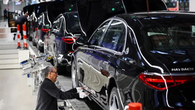 صورة لرجل يعمل على خط لصناعة السيّارات داخل مصنع لشركة مرسيدس-مايباخ.