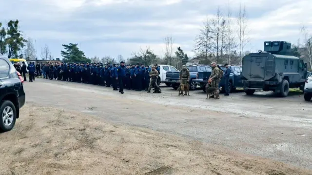 Поліцейські машини та шеренга людей