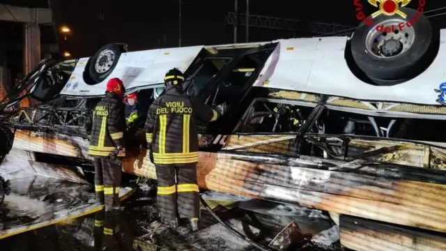 Restos del autobús vigilados por los bomberos. 