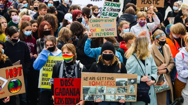 Estudantes e apoiadores participam do protesto pelo Clima, organizado pelo movimento Fridays for Future, também conhecido como Greve da Juventude pelo Clima, na Polônia, em 24 de setembro de 2021. Eles usam máscaras e seguram cartazes. 