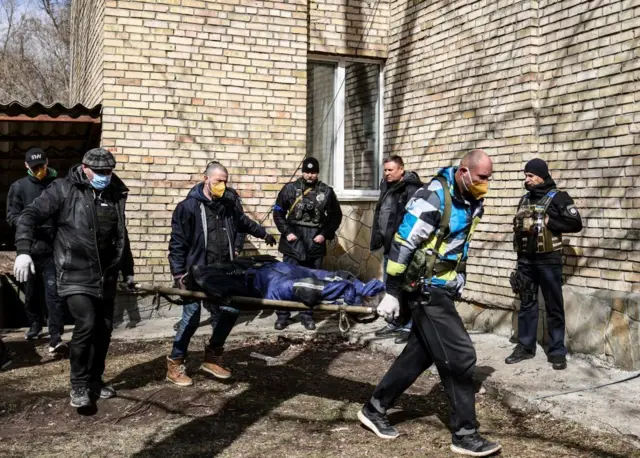 Тело погибшего мирного жителя выносят из здания школы в Буче, 4 апреля 2022 года