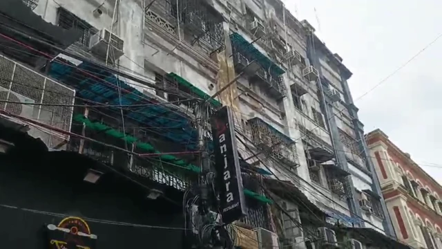 একটি বহুতল ভবনের একটি পাশ দেখা যাচ্ছে যেখানে বেশ কয়েকটি জানালা রয়েছে