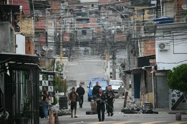 Policiais fortemente armados e pessoas na rua durante operação na favela