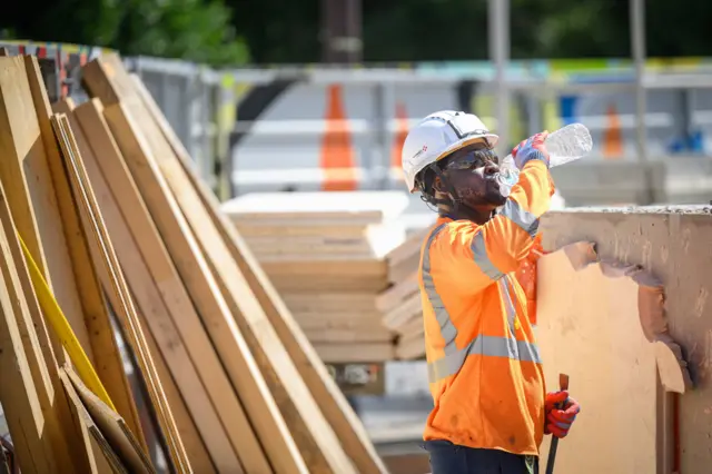 Pracownik chłodzi się wodą na placu budowy podczas fali upałów we Francji