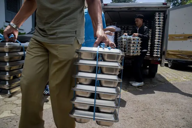 Petugas sekolah membawa makanan bergizi gratis untuk dibagikan kepada siswa SMA di SMA Negeri 20 Bandung, Jawa Barat, pada 14 April 2025.