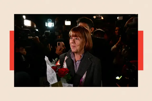 Gisèle Pelicot souriante et tenant un bouquet de roses rouges à la sortie du palais de justice d'Avignon 