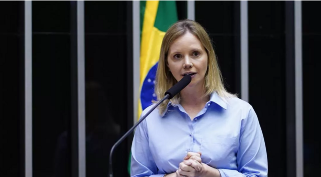 Dani Cunha discursa com bandeira do Brasil ao fundo