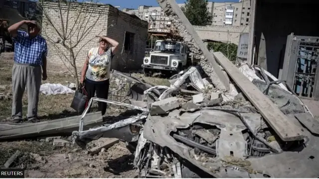 مواطنان أوكرانيان يقفان خارج مبنى للشقق السكنية دمرته ضربة صاروخية روسية في بوكروفسك بمنطقة دونيتسك