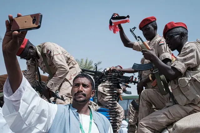 Mwanaume wa Sudan anapiga picha ya selfie na wanachama wa Rapid Support Forces (RSF), wakiwa na sare na bunduki, katika mji mkuu Khartoum tarehe 18 Juni 2019.