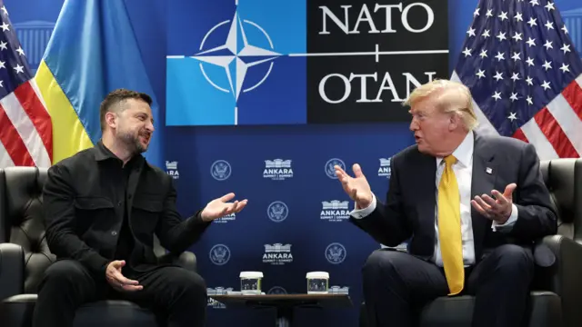 Зеленський і Трамп жестикулюють, сидячи і кріслах на тлі логотипу НАТО на стіні та прапорів