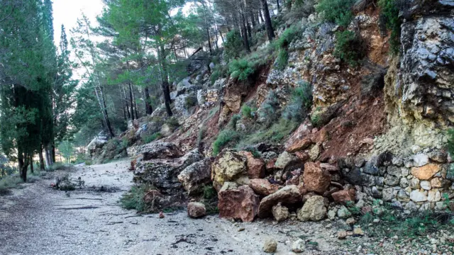 A mountain road is covered with rocks and mud following a landslide