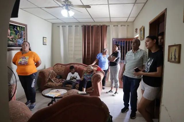 Myrelis Casique López viendo el televisor con otros familiares en la sala de una casa