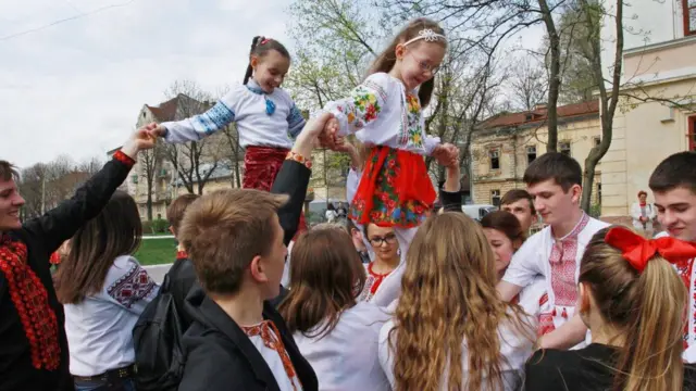 Діти різного віку в національному вбранні на вулиці під час свята показують виставу 