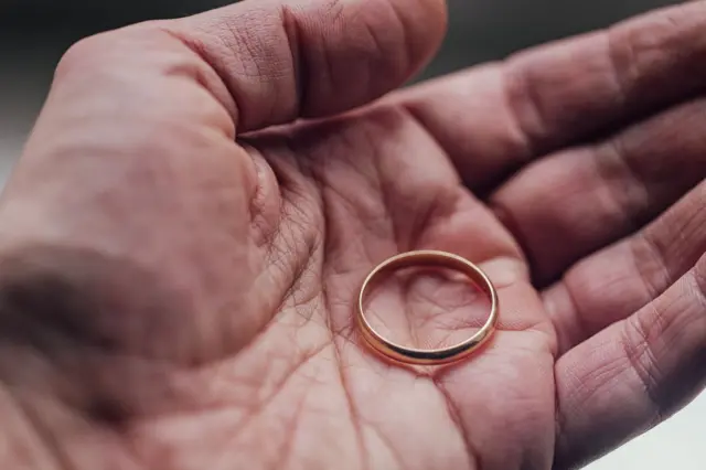 Main d'un homme tenant une bague dans la paume de sa main.